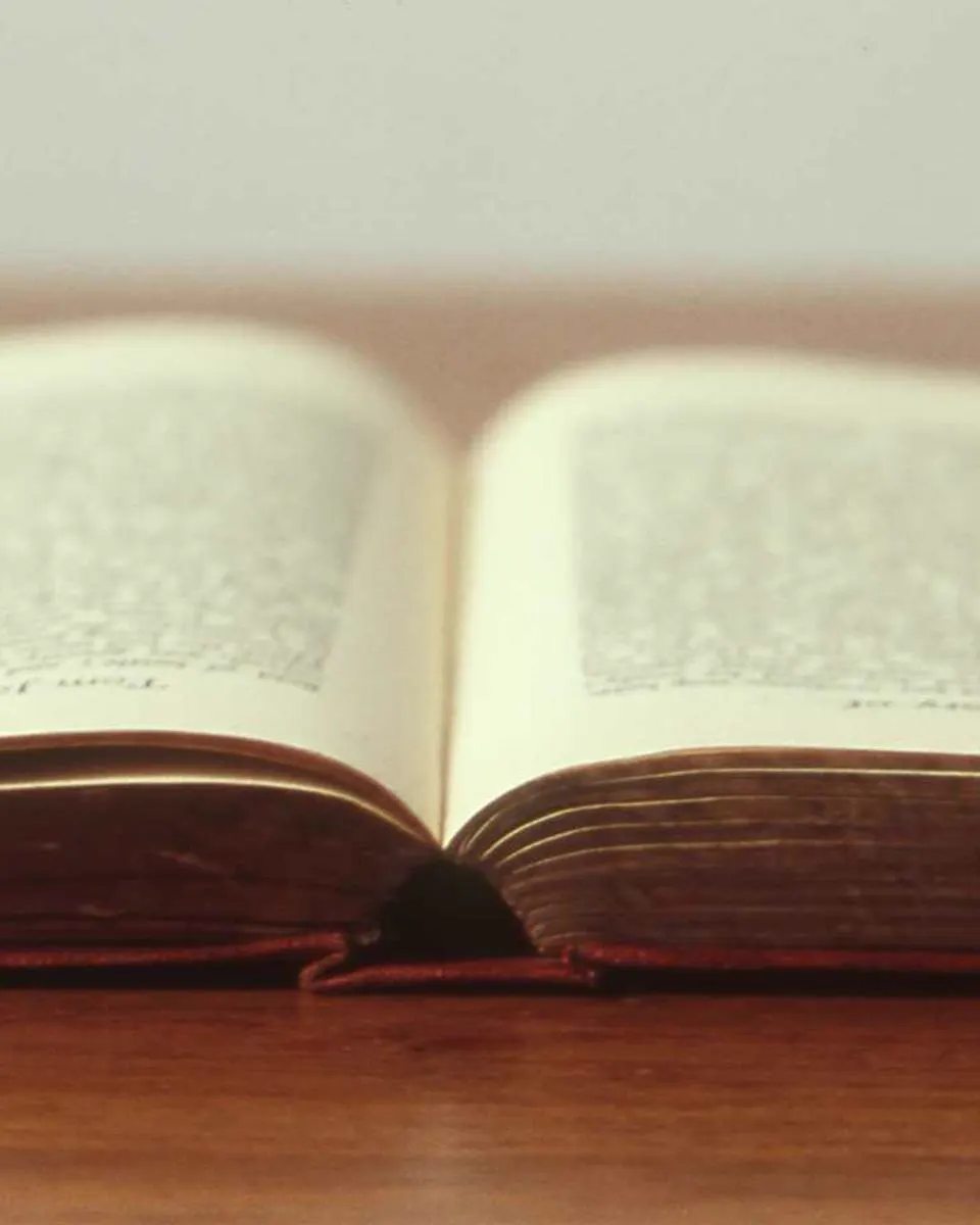 Livro aberto pousado numa mesa de madeira